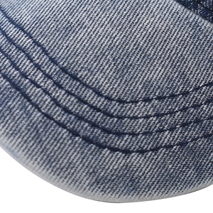 Macro shot of washed blue denim baseball cap featuring distressed texture and triple stitching