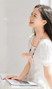 Pink portable neck fan weighing 195g shown worn by a model with a soft strap