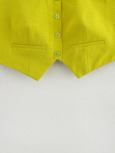 Dettaglio del gilet verde lime con trama in lino, bottoni monopetto e tasche con patta