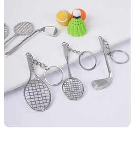Close-up of silver metal mini tennis, badminton and golf club keychains on white background