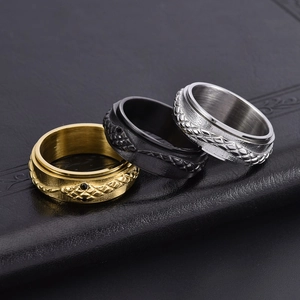 Detail of three rotating snake rings in gold, matte black, and silver with scale texture