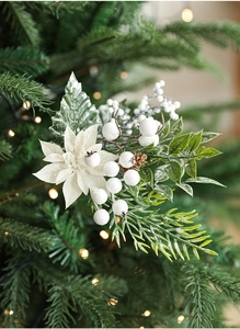 Detail of white poinsettia and snowy berries with warm glowing Christmas tree lights