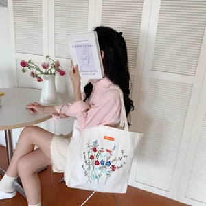 Detailed embroidery of colorful flowers on a white canvas tote bag for daily use