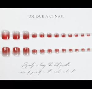 Détail de 24 faux ongles d'orteils dégradé rouge pailleté sur un fond blanc neutre