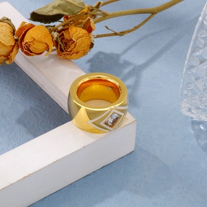 Close-up of gold stainless steel ring with white enamel and square zircon crystal