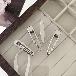 Set of four minimalist silver metal hair clips displayed on a soft jewelry tray