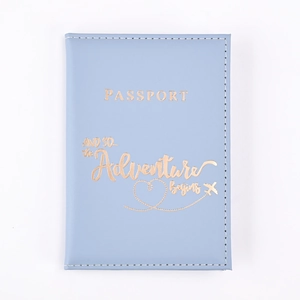 Detail of light blue PU leather passport holder with golden adventure quote engraving