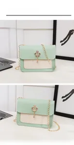 Detail view of mint green and cream crossbody bag with golden crown buckle and chain strap