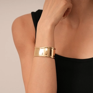 Detailed view of wide gold geometric cuff bracelet with a polished mirror finish on wrist