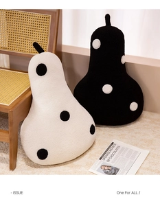 Chic pear-shaped plush pillows in black and white polka dots on a rattan chair