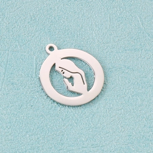 Macro shot of silver stainless steel round pendant featuring hollow Virgin Mary detail