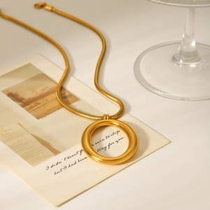 Elegant gold-tone snake chain necklace with a hollow oval pendant on a vintage card