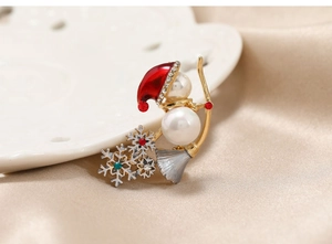 Macro shot of snowman Christmas brooch with rhinestones and faux pearls on silk