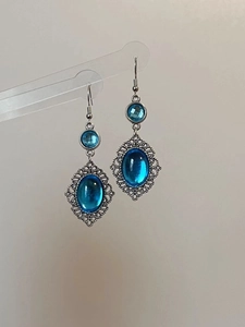 Detailed view of vintage blue resin oval earrings with intricate silver lace filigree hooks