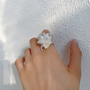 Detail showing the irregular silver flower ring with a round white pearl on a finger