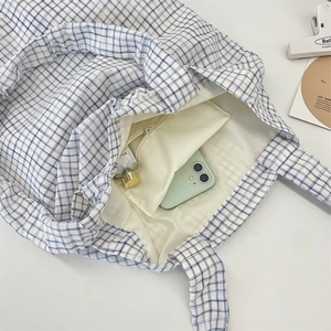 Close-up of blue checkered canvas tote bag interior with zipper pocket and lining