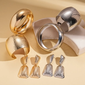 Three-piece set of gold and silver hammered metal open bracelets and woven earrings