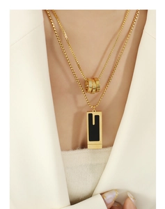 Close-up of double-layered gold necklace with triple-ring and black rectangle pendant