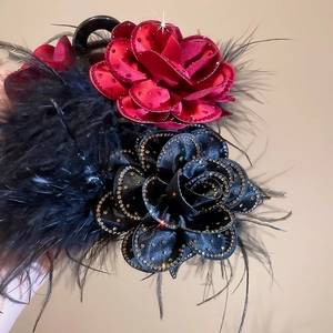 Detailed close-up of large satin flower hair clip with feathers and sparkling rhinestones