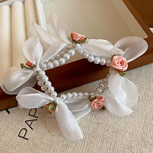 Détail du chouchou en perles avec nœuds en organza et roses en satin rose