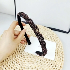 Detalle de una diadema negra trenzada con lujosas cuentas de cristal púrpura oscuro