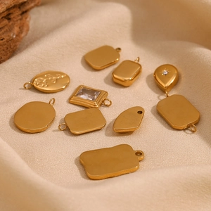 Detailed macro of 18K gold plated geometric pendants and rose relief charms on linen