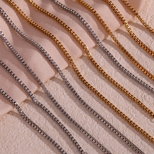 Detailed view of polished box chains in gold and silver finishes on satin fabric