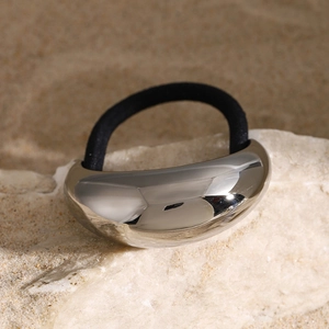 Black high-elastic hair tie with polished silver curved metal accent on stone background