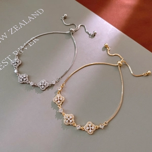 Detail of clover charms with clear zircons on adjustable gold and silver bracelets