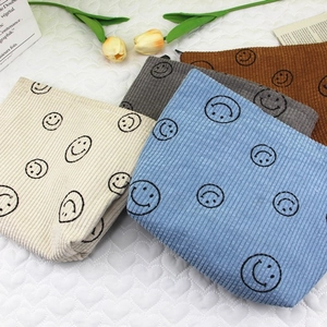 Corduroy makeup bags with smiley faces in cream, blue, grey, and brown colors