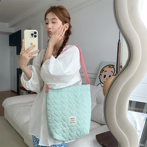 Detail of mint green heart quilted tote bag with pink straps and large storage capacity