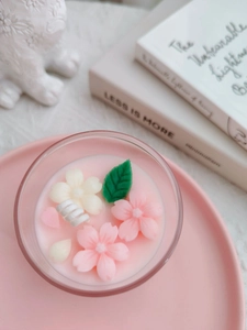 Top view of handmade pink scented candle in glass with detailed cherry blossom wax flowers