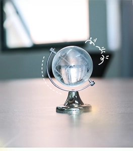 Macro detail of a transparent crystal globe with frosted map on a silver metal stand