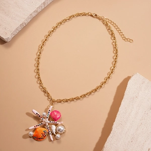 Golden starfish and shell necklace with pearls and rhinestones on a beige background
