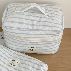 Close-up of quilted blue striped cosmetic bag set with soft texture and metal zipper