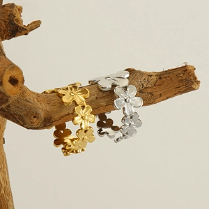 Close-up of gold and silver flower rings with matte finish on a natural wood branch