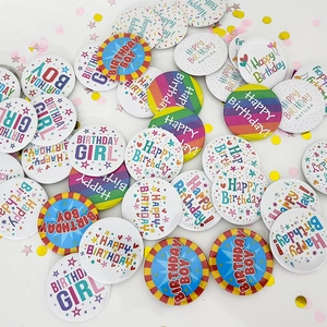 Flat lay of colorful tinplate birthday badges with confetti decorations for parties
