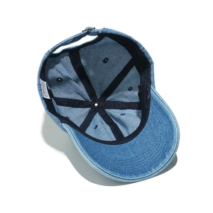 Internal view of a washed blue denim baseball cap featuring reinforced tape and metal buckle