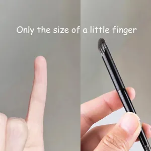 Détail du petit pinceau correcteur rond comparé à la taille d'un petit doigt