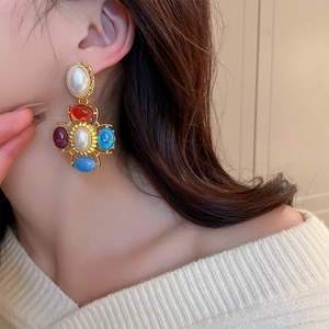 Gros plan de boucles d'oreilles baroques avec pierres colorées et perle sur un mannequin
