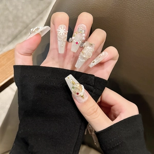 Faux ongles de Noël blancs avec flocons de neige, perles et motifs d'étoiles dorées