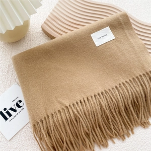 Detail of camel fringe scarf showing soft cashmere texture and woven brand label