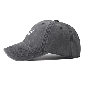 Detail of white dog embroidery on washed cotton dark grey baseball cap surface