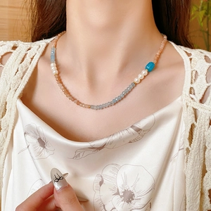 Detail of square aquamarine and pearl beaded necklace with gold accents on neck