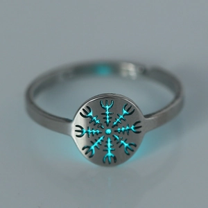 Macro shot of silver stainless steel ring with a glowing blue hollow symbol in the dark
