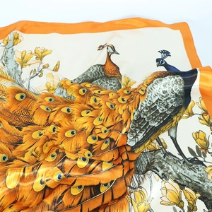 Luxurious orange silk scarf featuring an elegant peacock and floral pattern print
