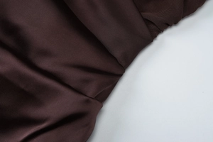 Gros plan détaillé du tissu en satin marron avec drapé élégant et fini soyeux et lisse