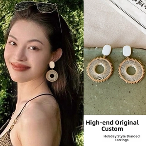 Detail of bohemian woven hoop earrings with white enamel studs and gold metallic edges