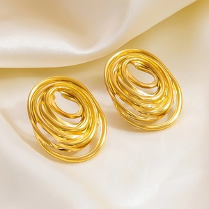 Detailed view of polished gold hollow spiral earrings on elegant silk fabric background