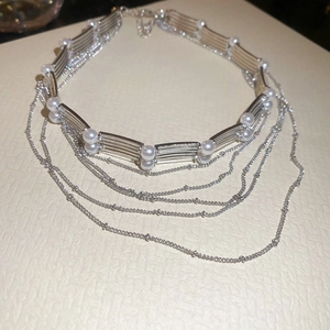 Détail du collier de perles multicouche avec barres métalliques argentées et chaînes